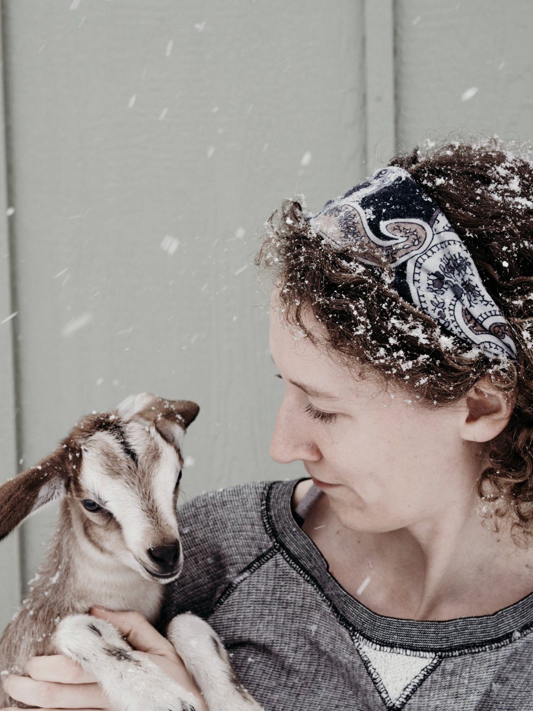 Laura holding a baby goat in falling snow